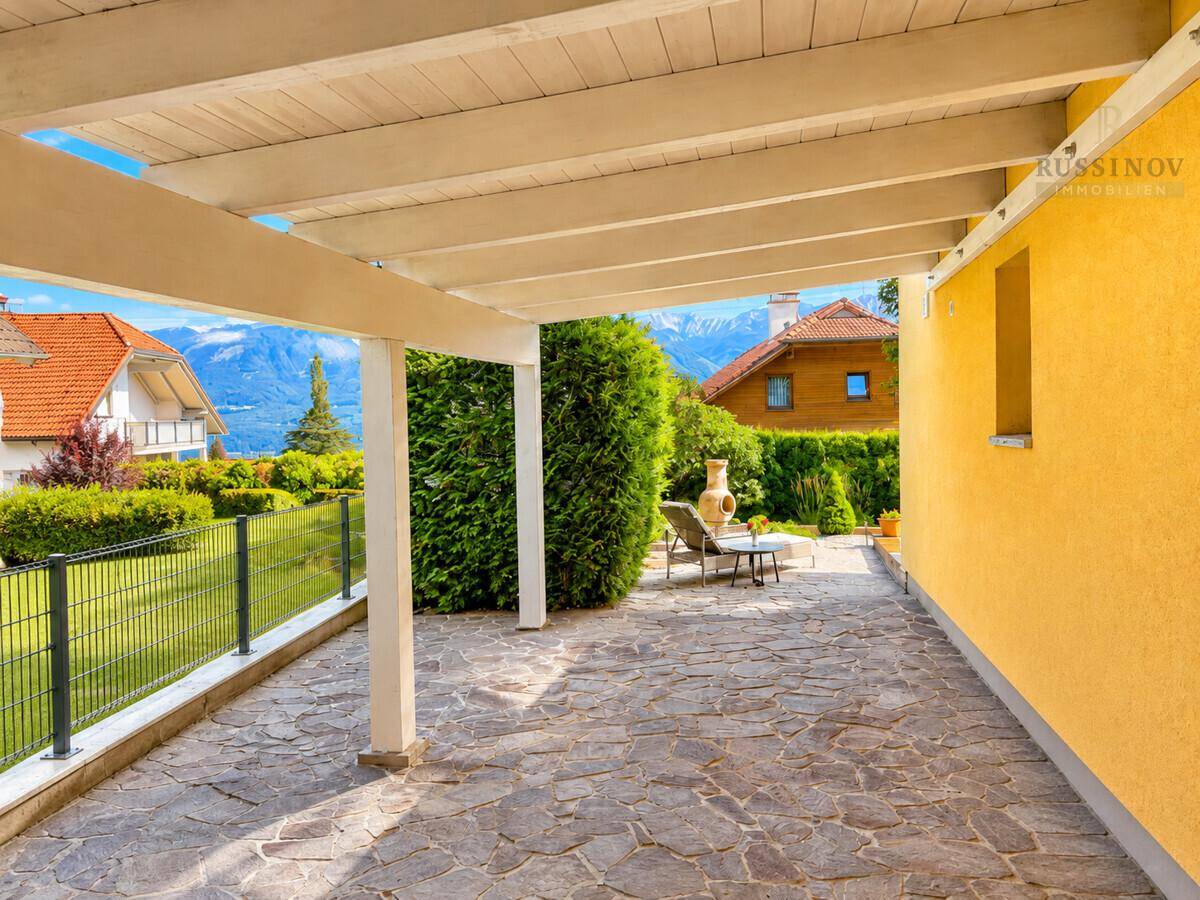 Überdachte Terrasse mit Steinboden und weitem Blick auf die Berge.