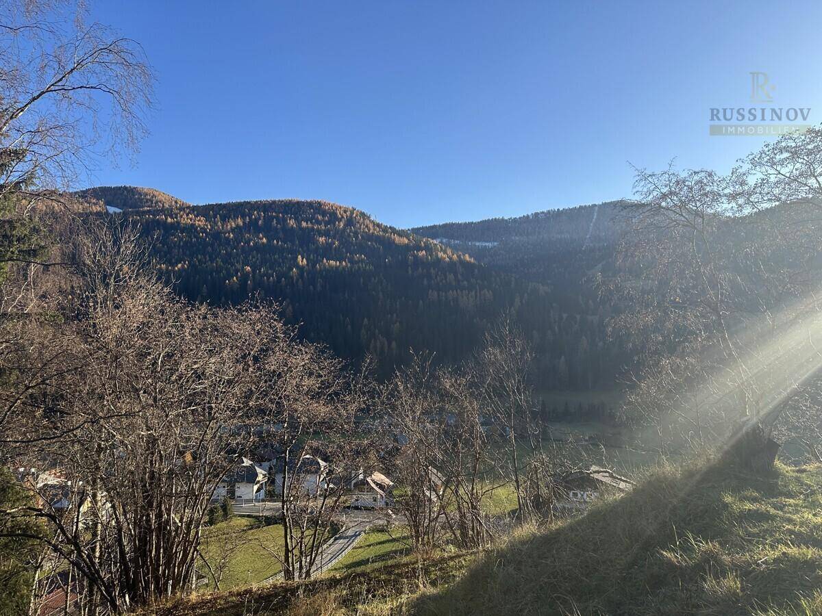 Weitläufiger Blick auf die umliegende Berglandschaft und das Tal unter blauem Himmel.