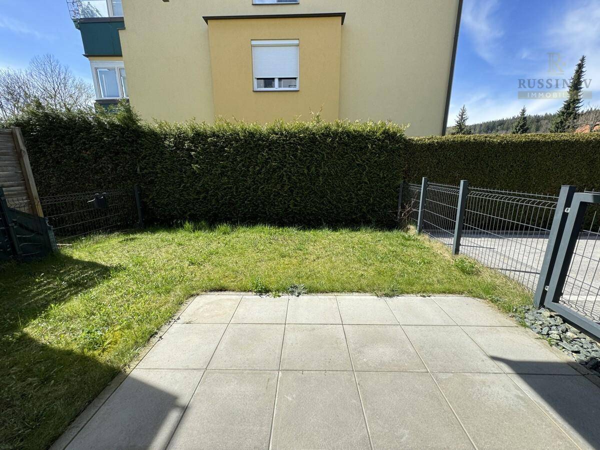 Kleiner privater Gartenbereich mit Rasenfläche und gepflasterter Terrasse.