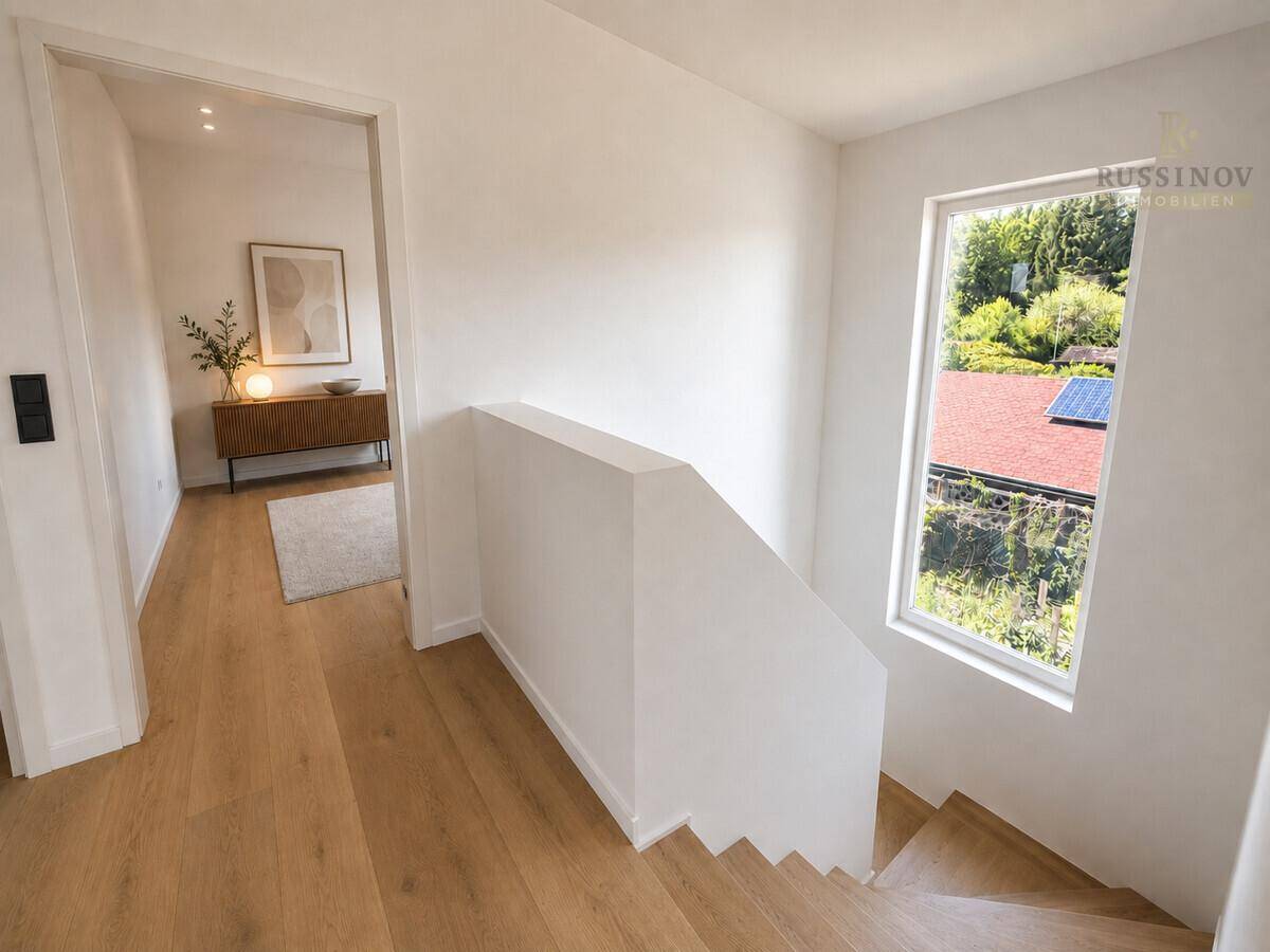 Heller Flur mit Holztreppe und Fenster, das einen Blick auf die Umgebung bietet.