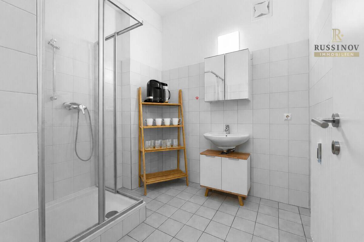 Modernes Badezimmer mit Duschkabine, Waschbecken und weißen Fliesen, funktional und sauber.