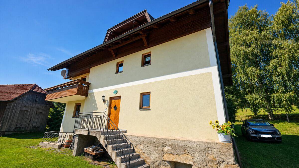 Ansicht des Hauses von der Seite mit Eingangsbereich, Außentreppe und gepflegter Umgebung.