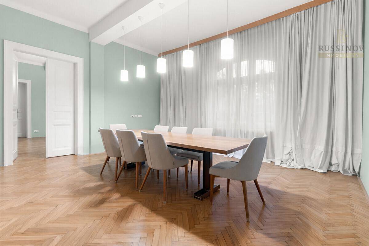 Eleganter Essbereich mit großem Holztisch, modernen Pendelleuchten und Fischgrätparkettboden.