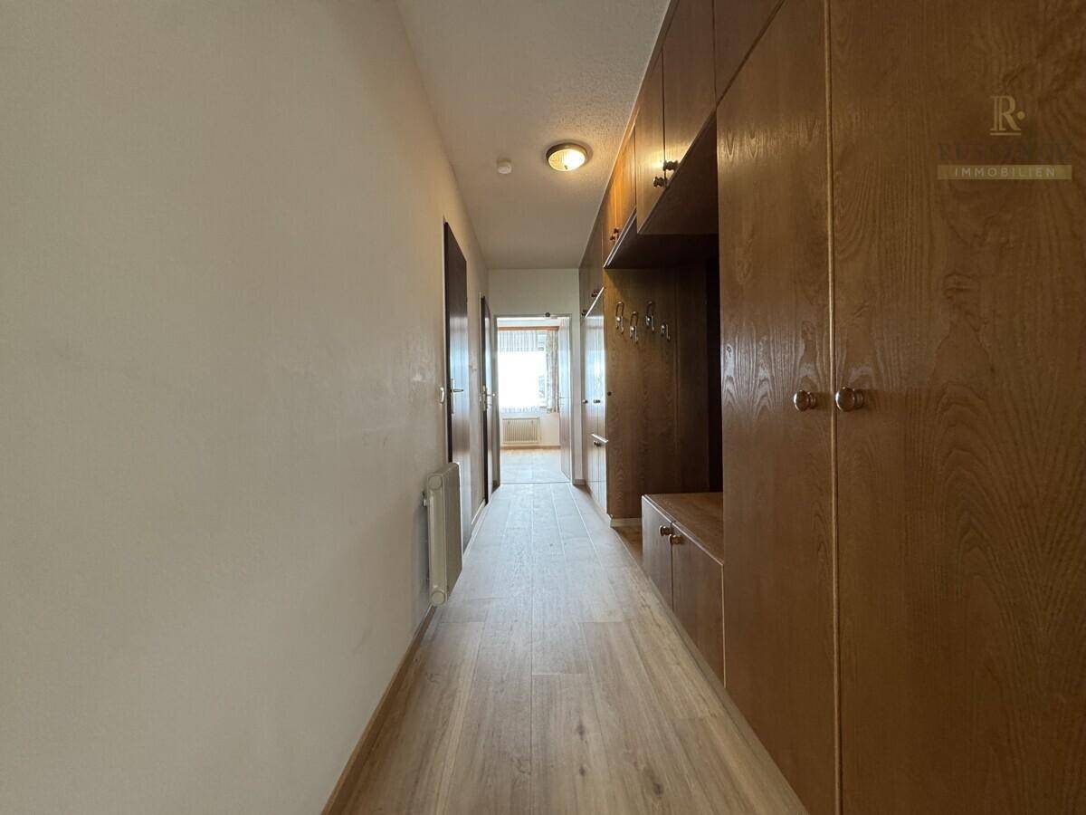 Langer Flur mit praktischen Einbauschränken aus Holz und hellem Laminatboden.