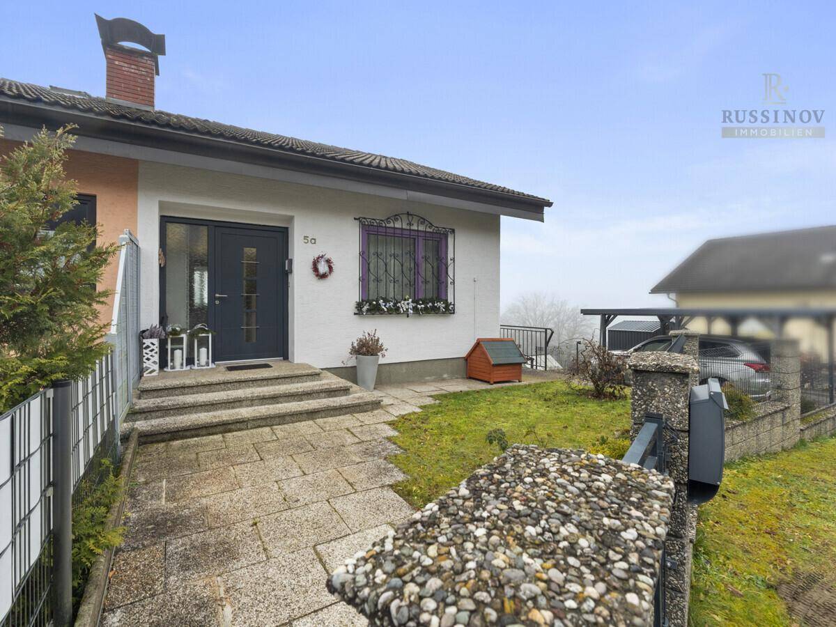 Eingangsbereich des Hauses mit gepflastertem Weg, Stufen und kleiner Rasenfläche.