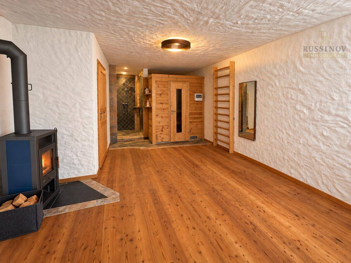 Geräumiger Wellnessbereich mit Sauna, Holzofen und Holzboden, ideal zur Entspannung.
