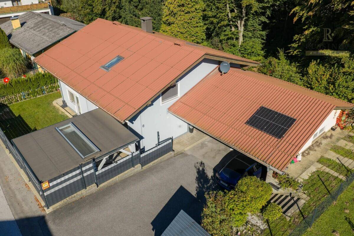 Luftaufnahme des Hauses mit rotem Ziegeldach, Solarpaneelen und umgebender grüner Landschaft.