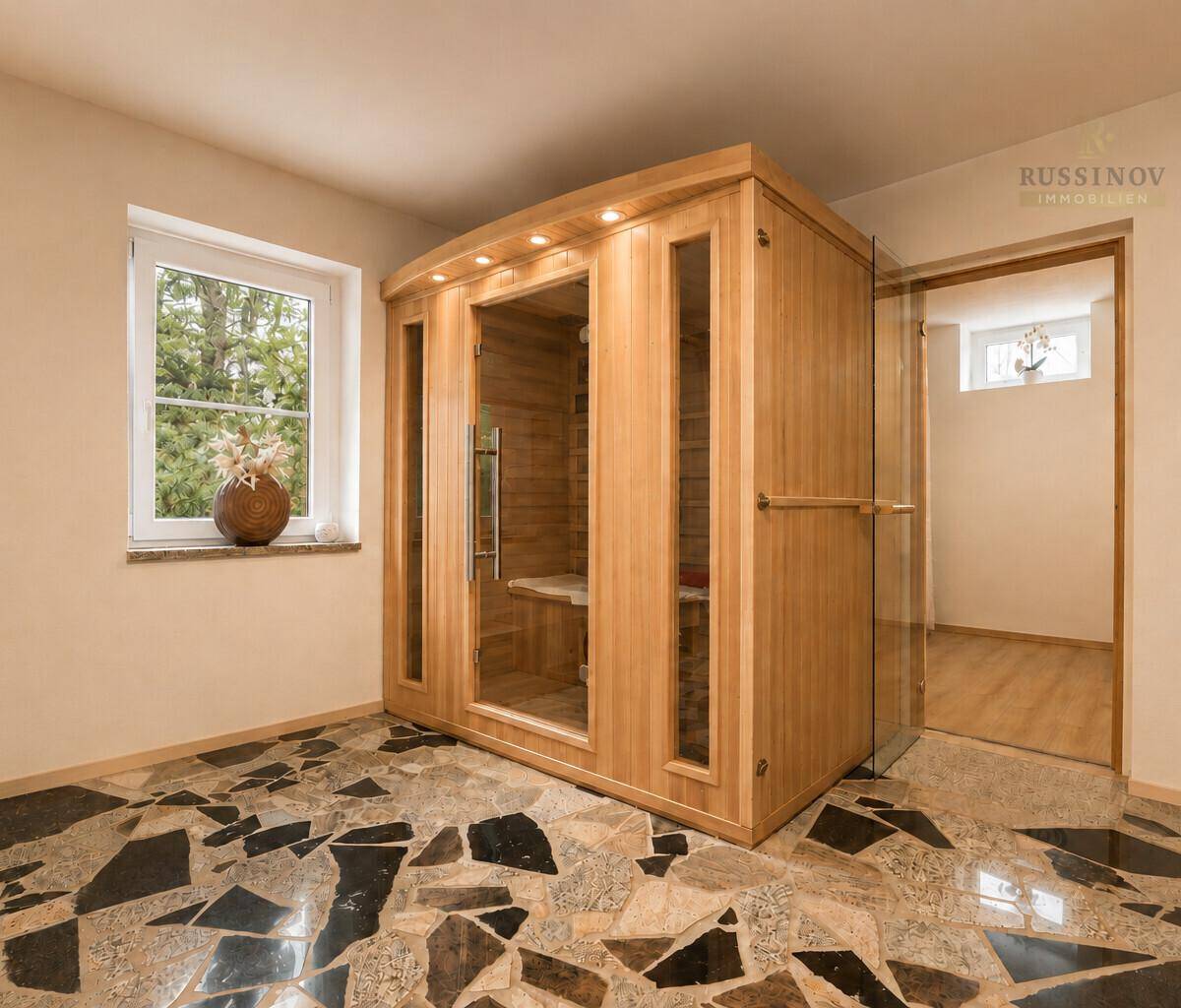 Moderne Saunakabine in einem Raum mit auffälligem dunklem Steinboden und Fenster.