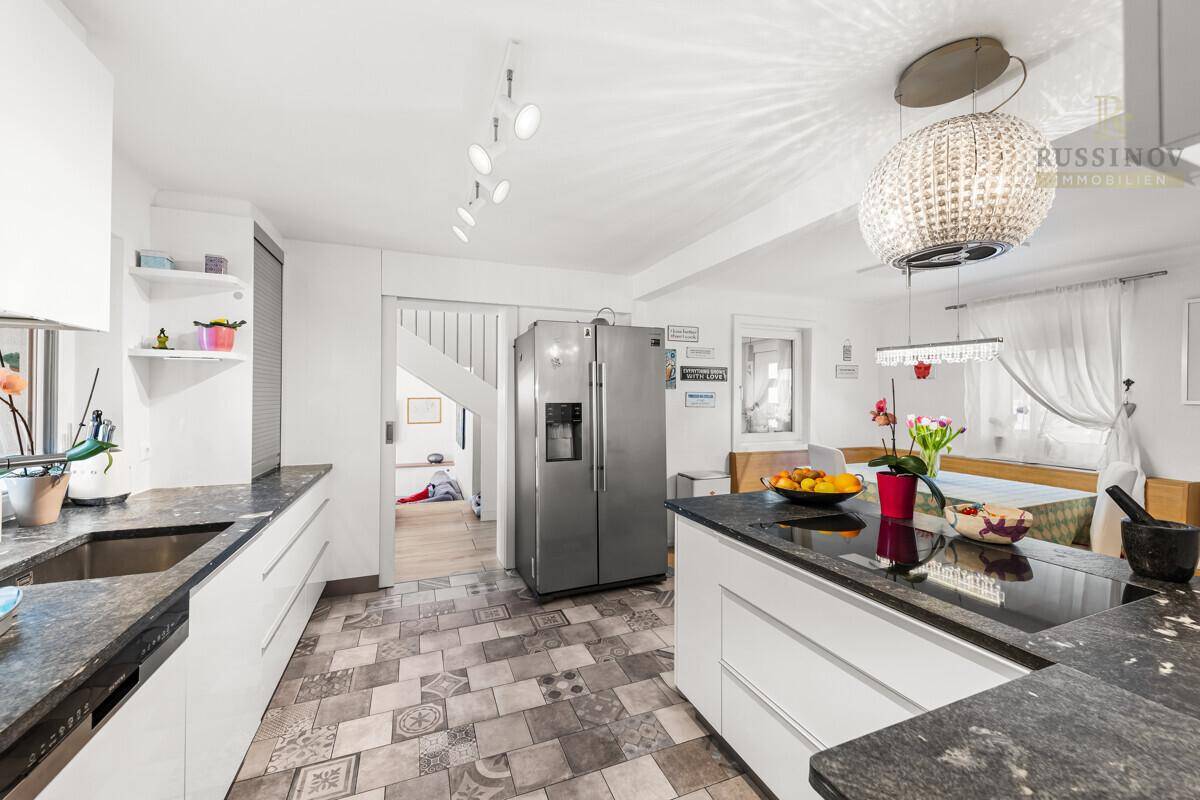 Moderne Küche mit Kücheninsel, dunklen Granitarbeitsplatten und stilvollen Fliesenböden.