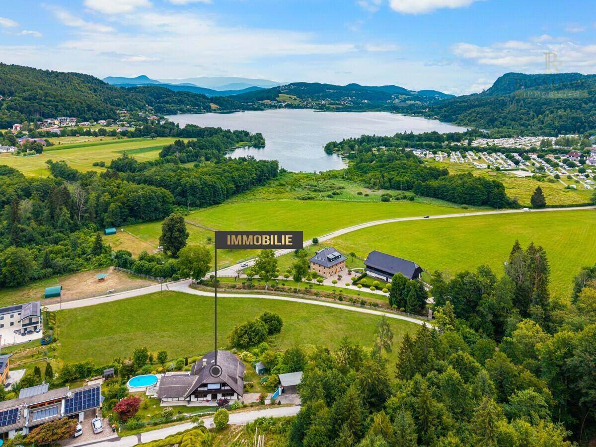 Luftaufnahme des Anwesens mit See- und Bergblick, umgeben von grüner Landschaft.