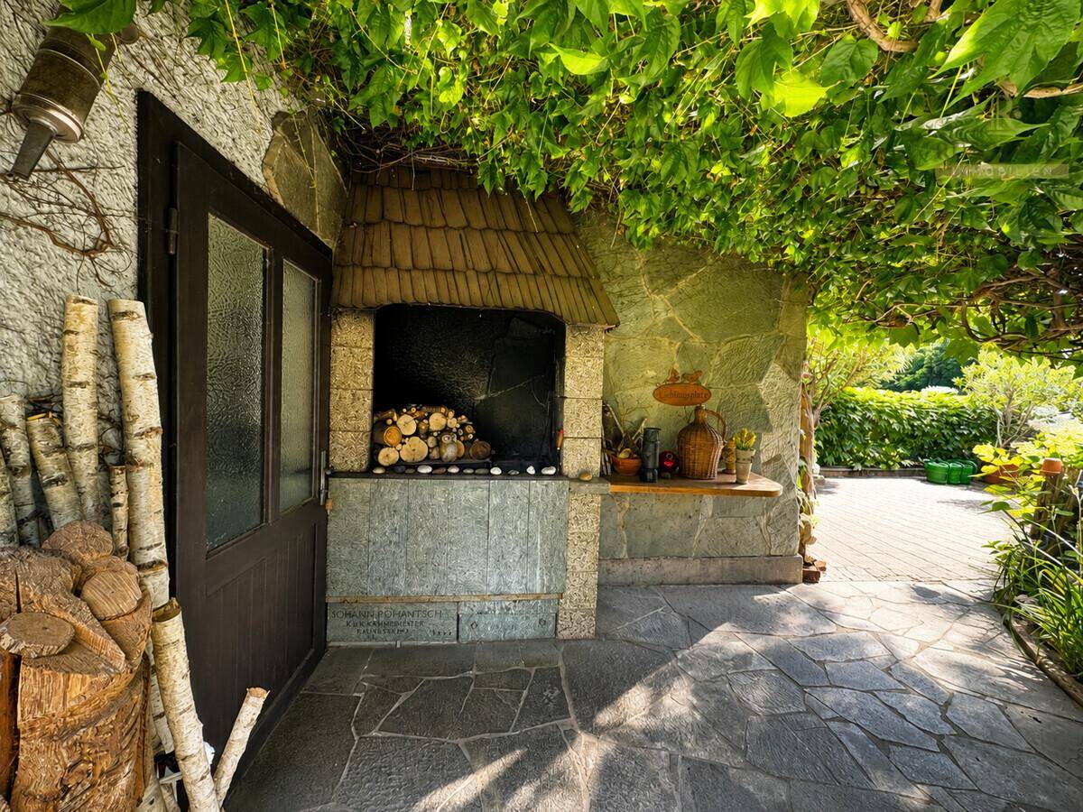 Gemütlicher Außenbereich mit überdachtem Grillplatz und Holzstapel, ideal für gesellige Abende.