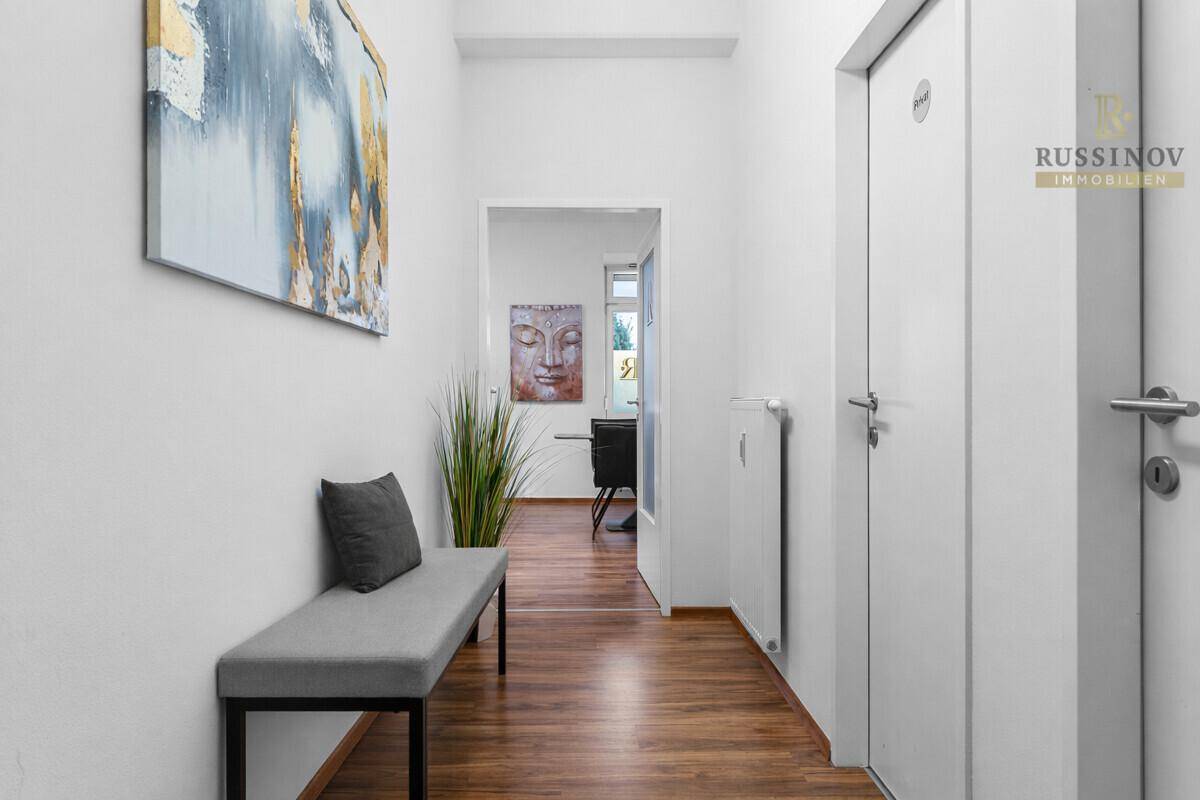 Heller Flur mit Holzboden, einer Sitzbank und Zugang zu weiteren Räumen, modern eingerichtet.