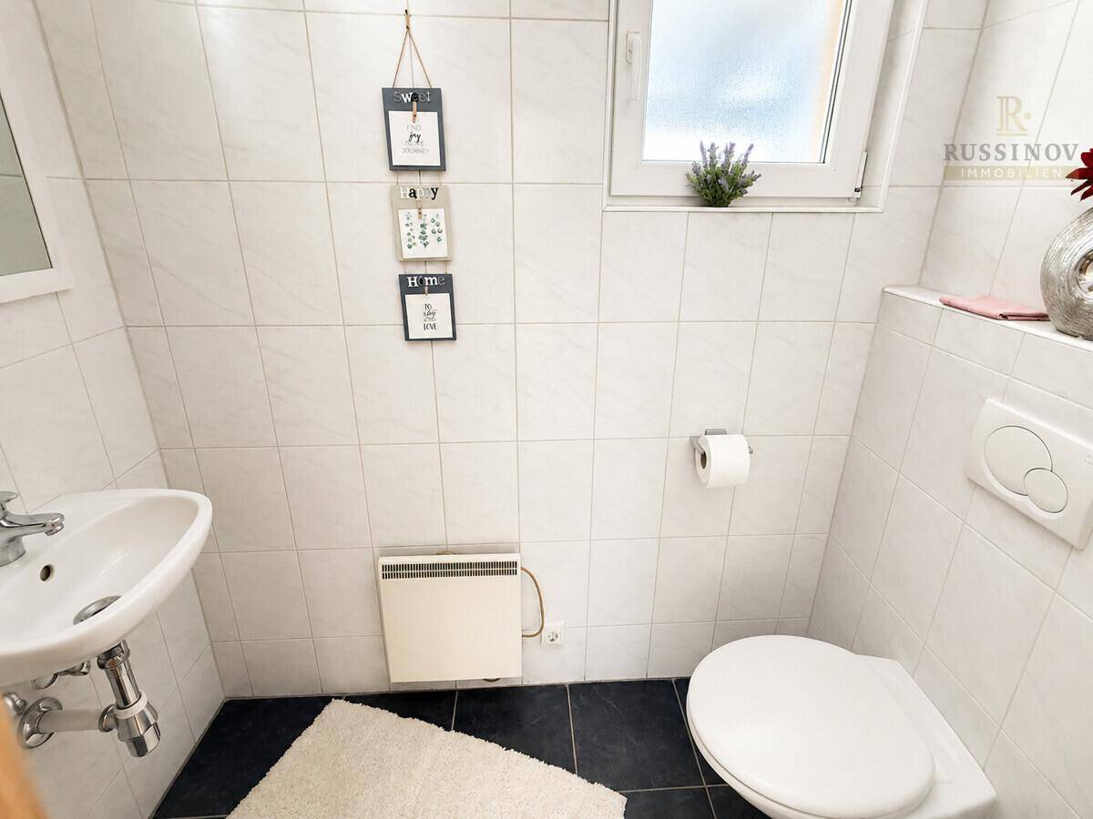 Kleines Gäste-WC mit Fenster, Waschbecken und Wandheizung.
