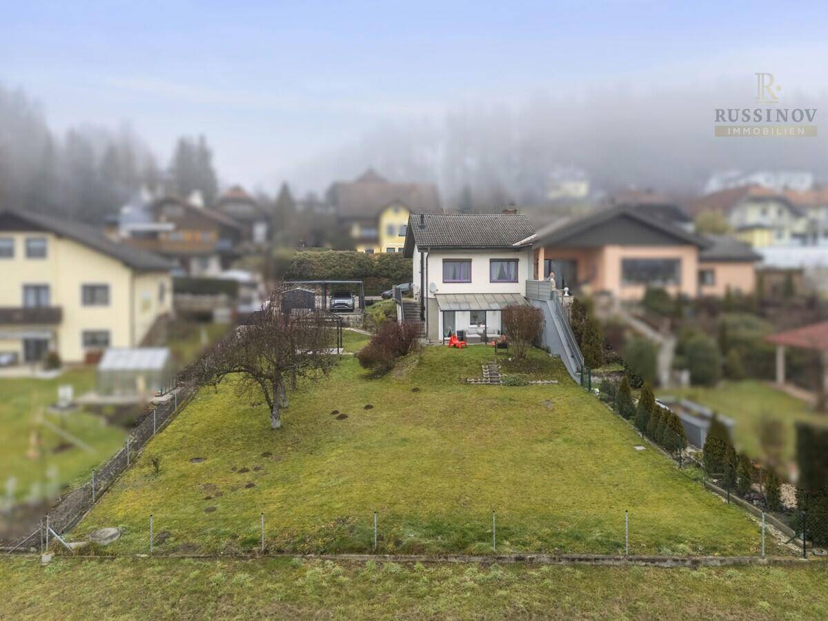 Weitläufiger Blick auf das Haus mit großem Garten und umliegender Wohnbebauung in nebliger Landschaft.