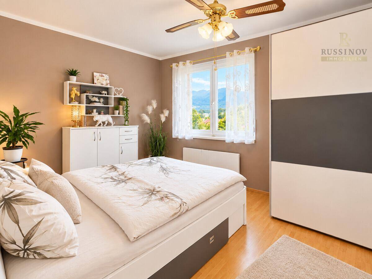 Schlafzimmer mit Doppelbett, Kleiderschrank und Fenster mit Bergblick.
