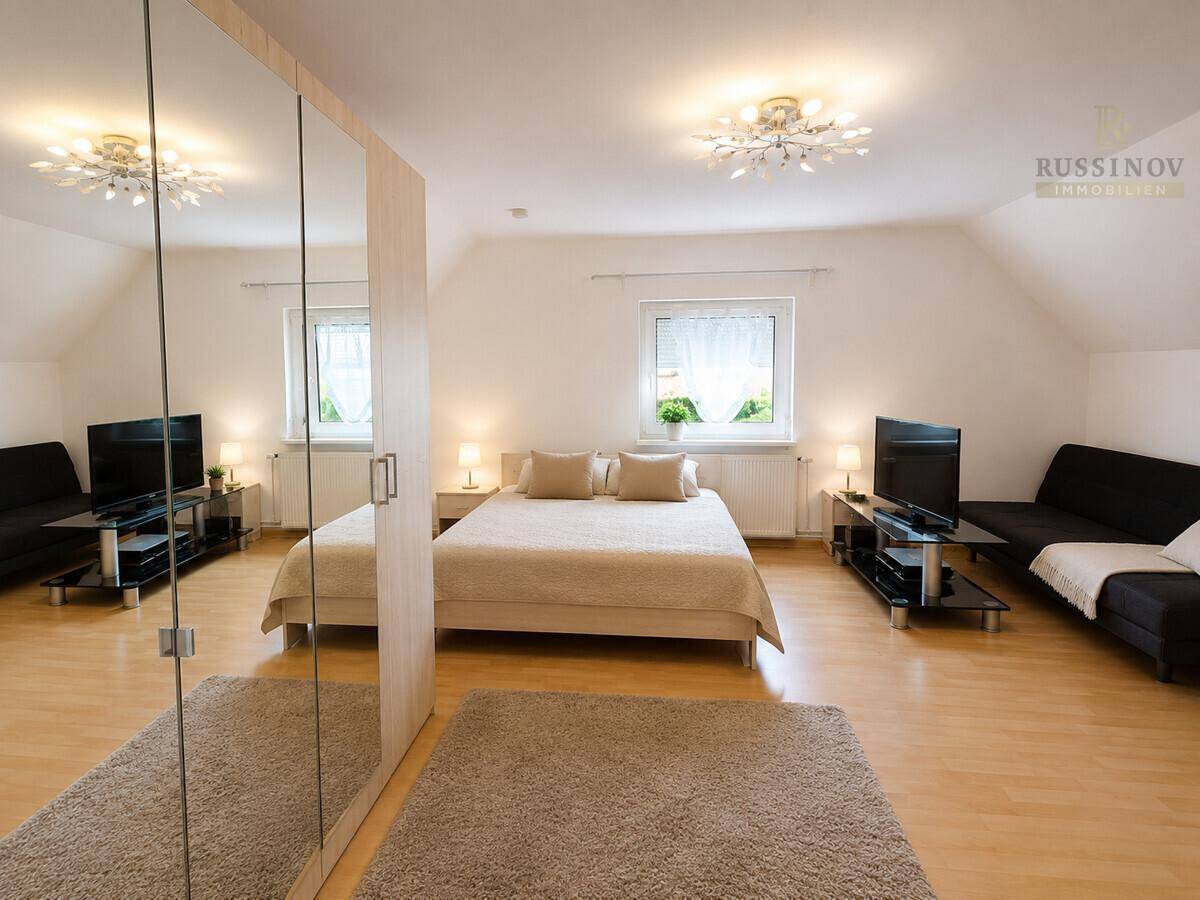 Geräumiges Schlafzimmer mit Doppelbett, Holzfußboden und Dachschrägen, hell und funktional eingerichtet.