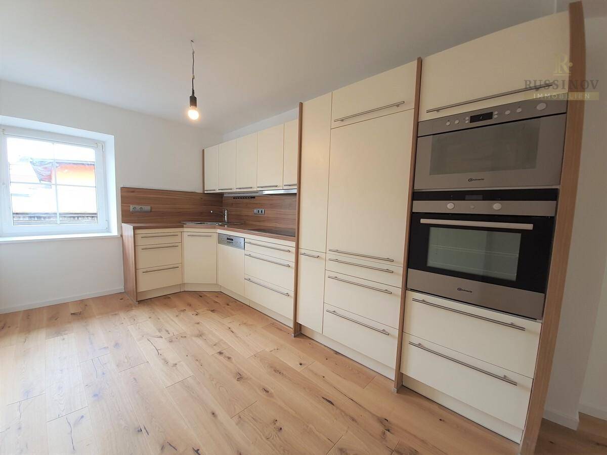 Moderne Einbauküche in hellem Beige mit integrierten Geräten und Holzarbeitsplatte.