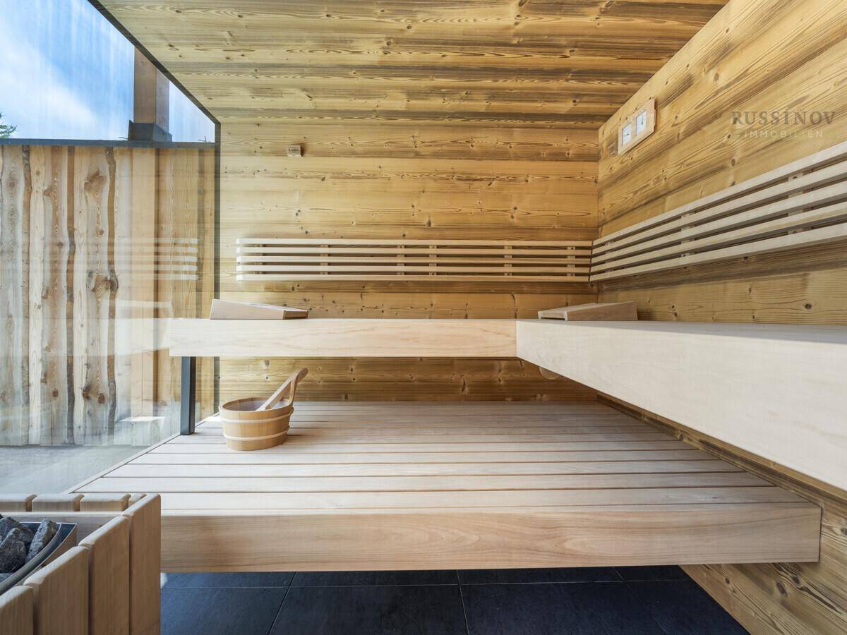 Moderne Holzsauna mit breiten Bänken und Glasfront für ein helles Wellness-Erlebnis.