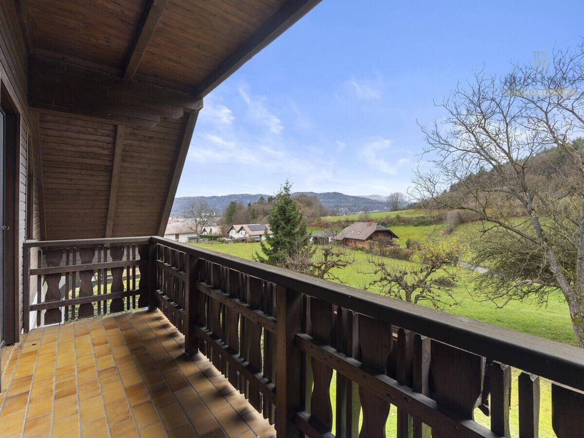 Gemütlicher Balkon mit Fliesenboden und Holzgeländer, bietet einen weiten Blick auf die grüne Landschaft.