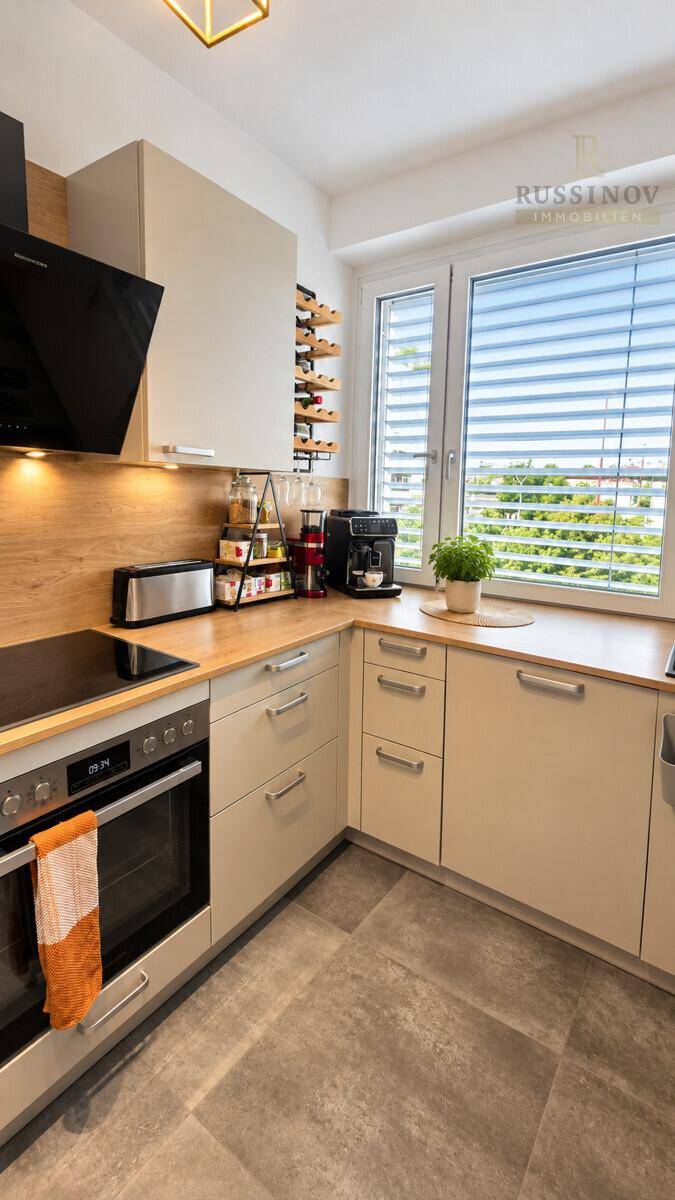 Moderne Einbauküche mit hellen Schränken, Holz-Arbeitsplatte und Fenster.