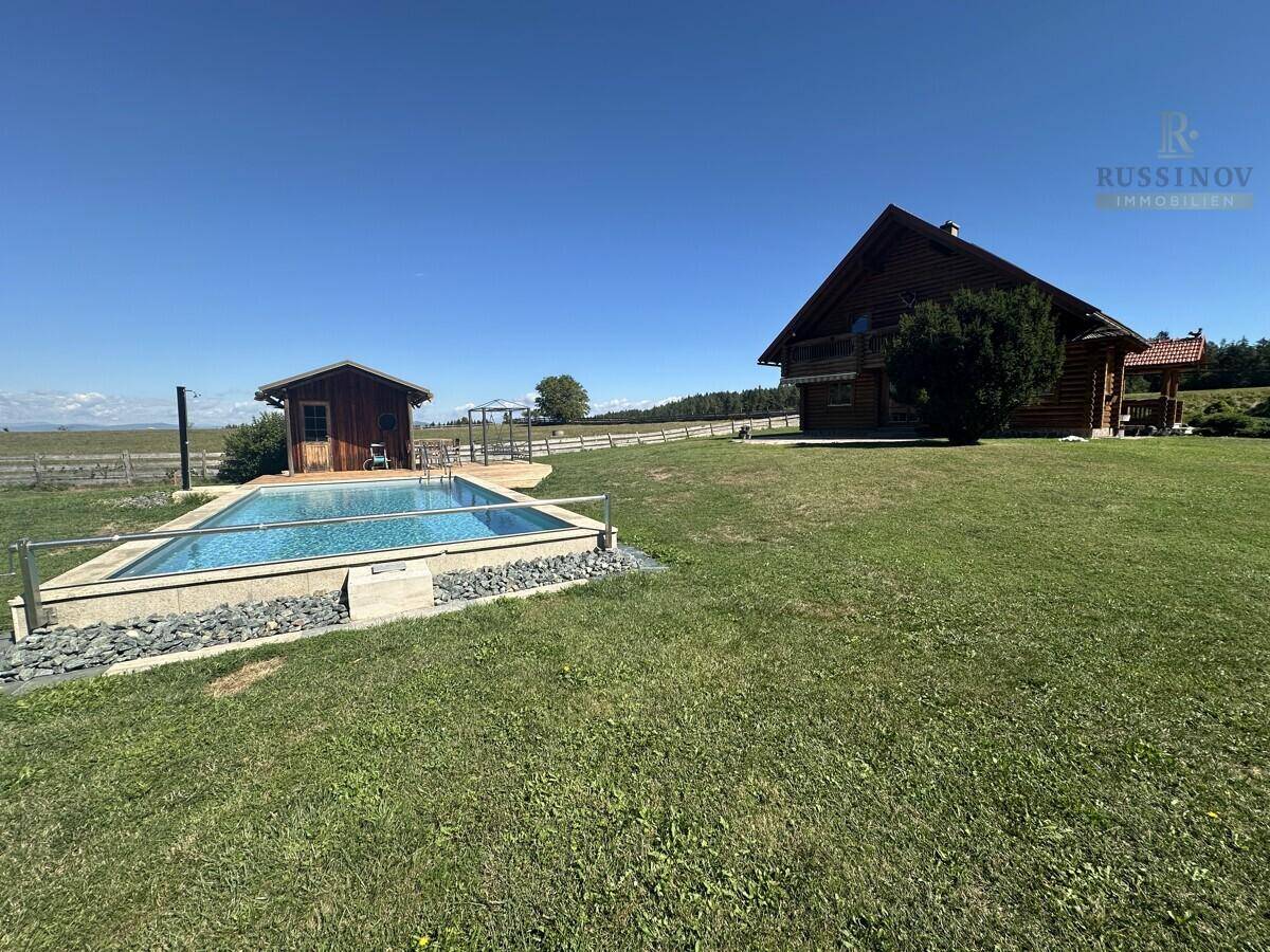 Weitläufiges Anwesen mit Holzhaus, Außenpool und Gartenhaus in ländlicher, sonniger Umgebung.