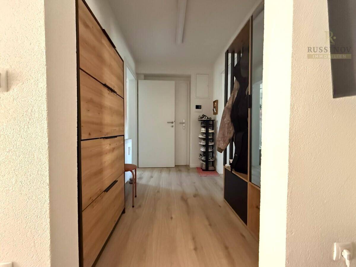 Heller Flur mit Holzschuhschrank, Garderobe und Laminatboden.