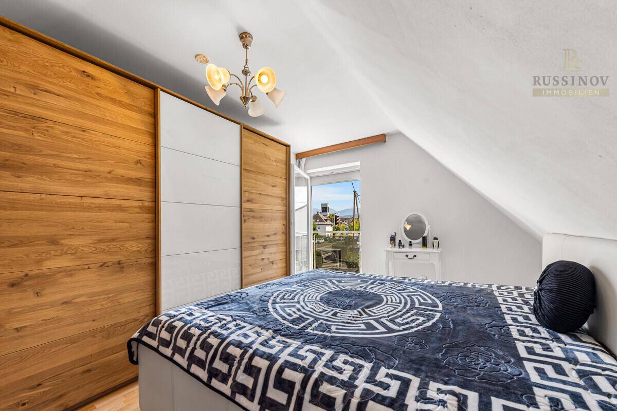 Schlafzimmer im Dachgeschoss mit Einbauschränken aus Holz und schräger Decke.