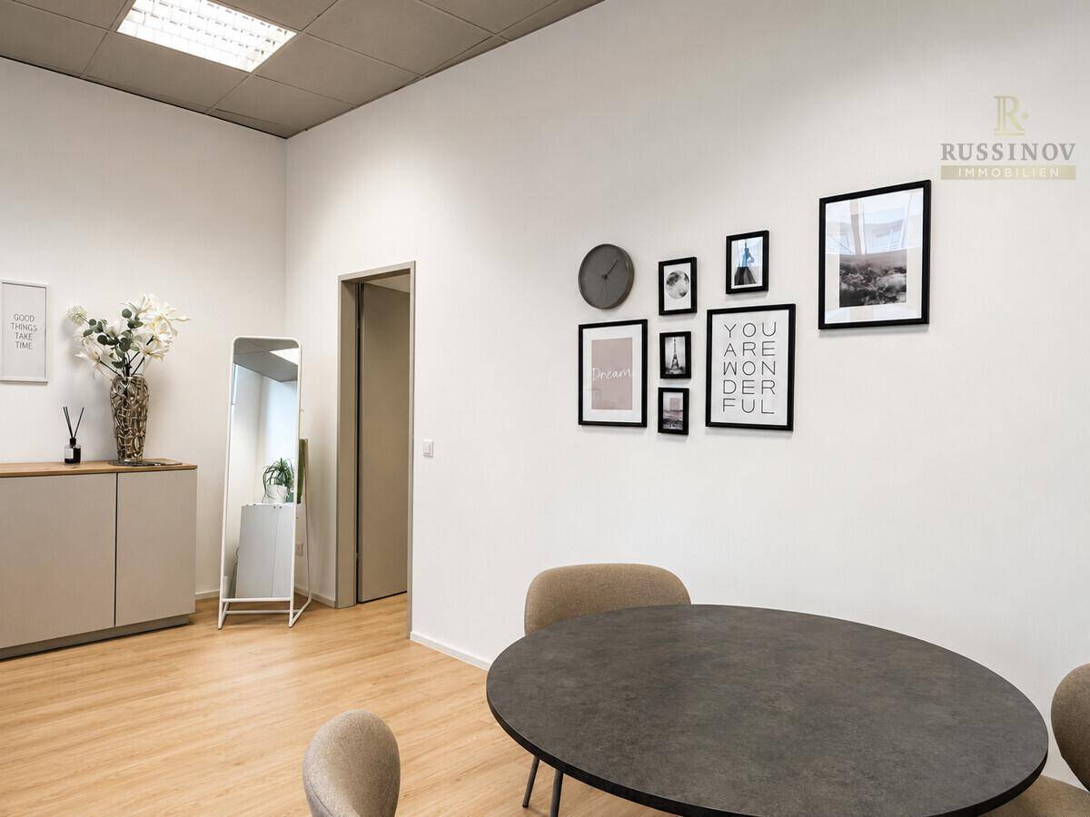 Heller Büroraum mit modernem Tisch, Stühlen und dekorativen Bildern an der Wand, bereit zur Nutzung.