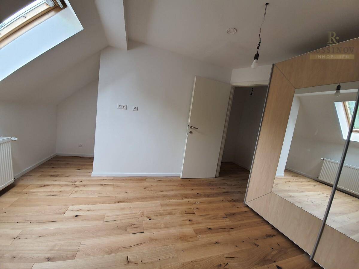 Geräumiges Schlafzimmer im Dachgeschoss mit Holzboden und Dachfenstern für viel Licht.