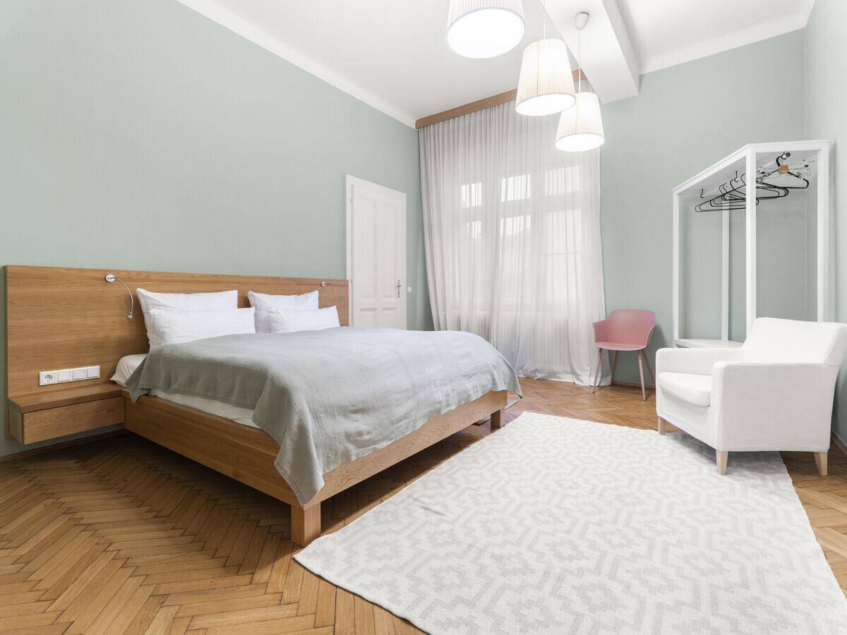 Geräumiges Schlafzimmer mit Holzbett, Teppich und hellgrünen Wänden, ideal zum Entspannen.