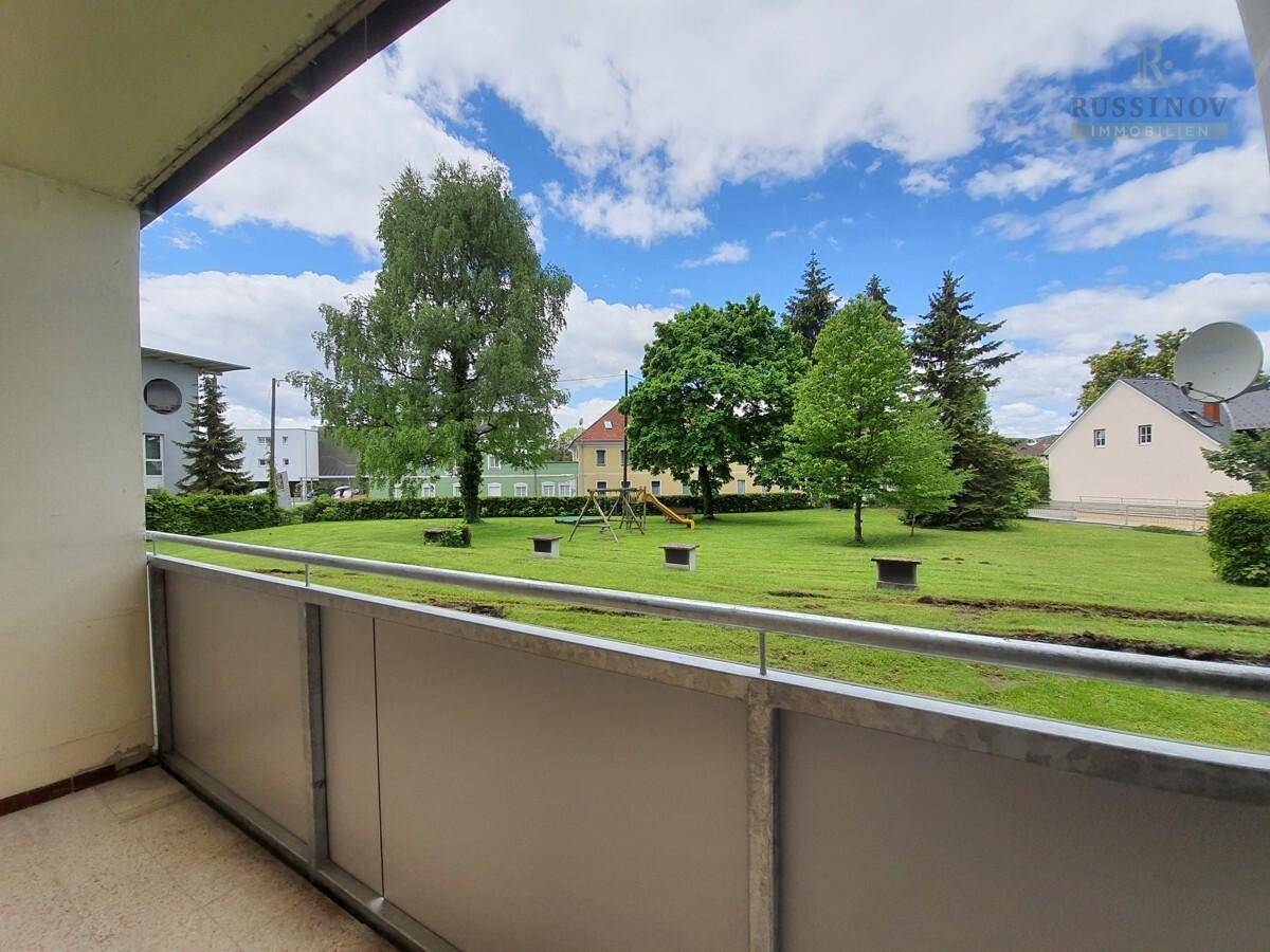Balkon mit Blick auf eine grüne Wiese und einen kleinen Spielplatz.