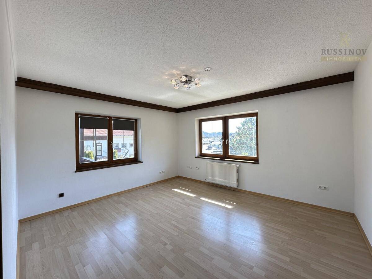 Geräumiges Zimmer mit hellem Laminatboden und zwei Fenstern, bereit zur individuellen Gestaltung.