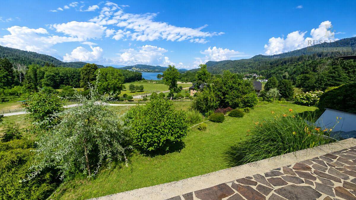 Weitläufiger Gartenbereich mit gepflegtem Rasen und Panoramablick auf den See und die Berge.