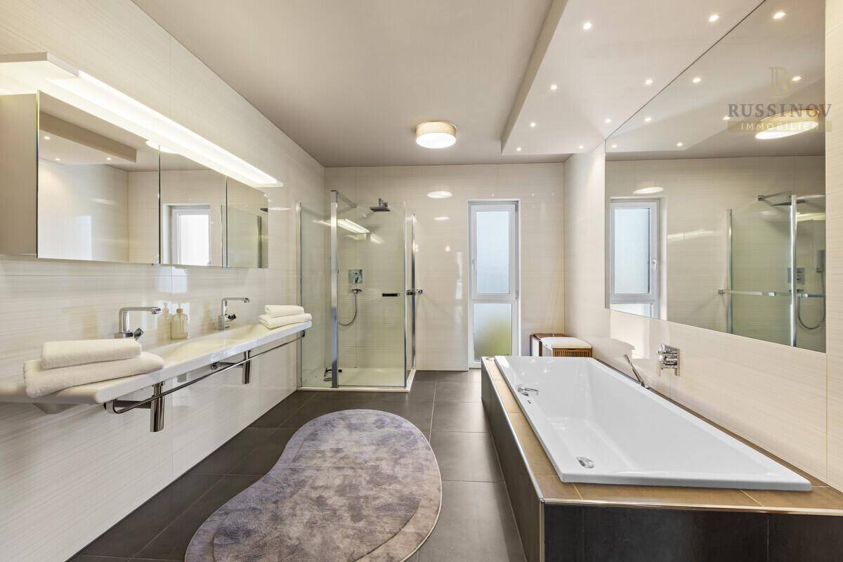 Modernes Badezimmer mit Badewanne, großer Dusche und Doppelwaschbecken.
