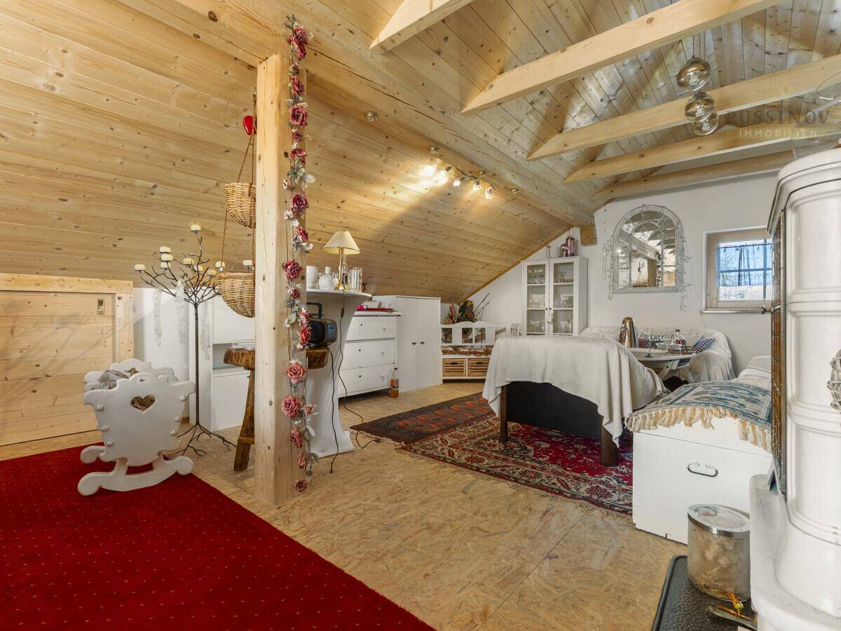 Gemütlicher Dachbodenraum mit viel Holzverkleidung, schrägen Decken und traditionellem Kachelofen.