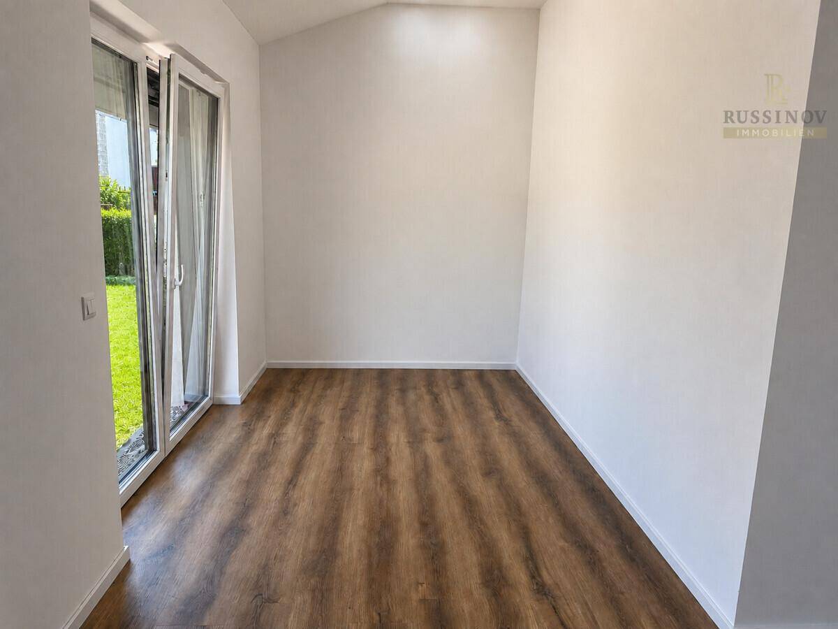 Helles Zimmer mit Laminatboden und direktem Zugang zum grünen Gartenbereich.