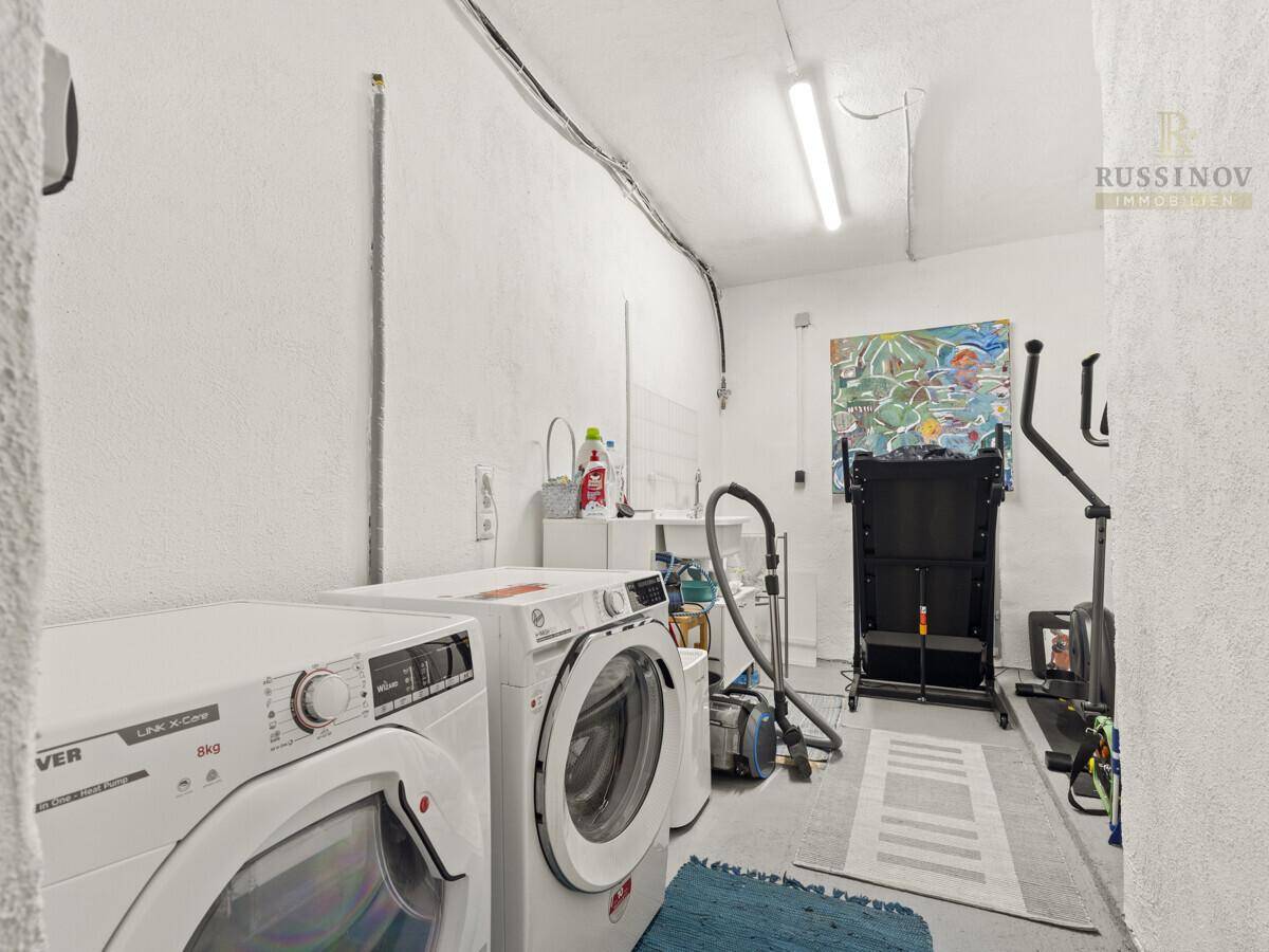 Praktischer Waschraum mit Waschmaschine, Trockner und Platz für Sportgeräte.