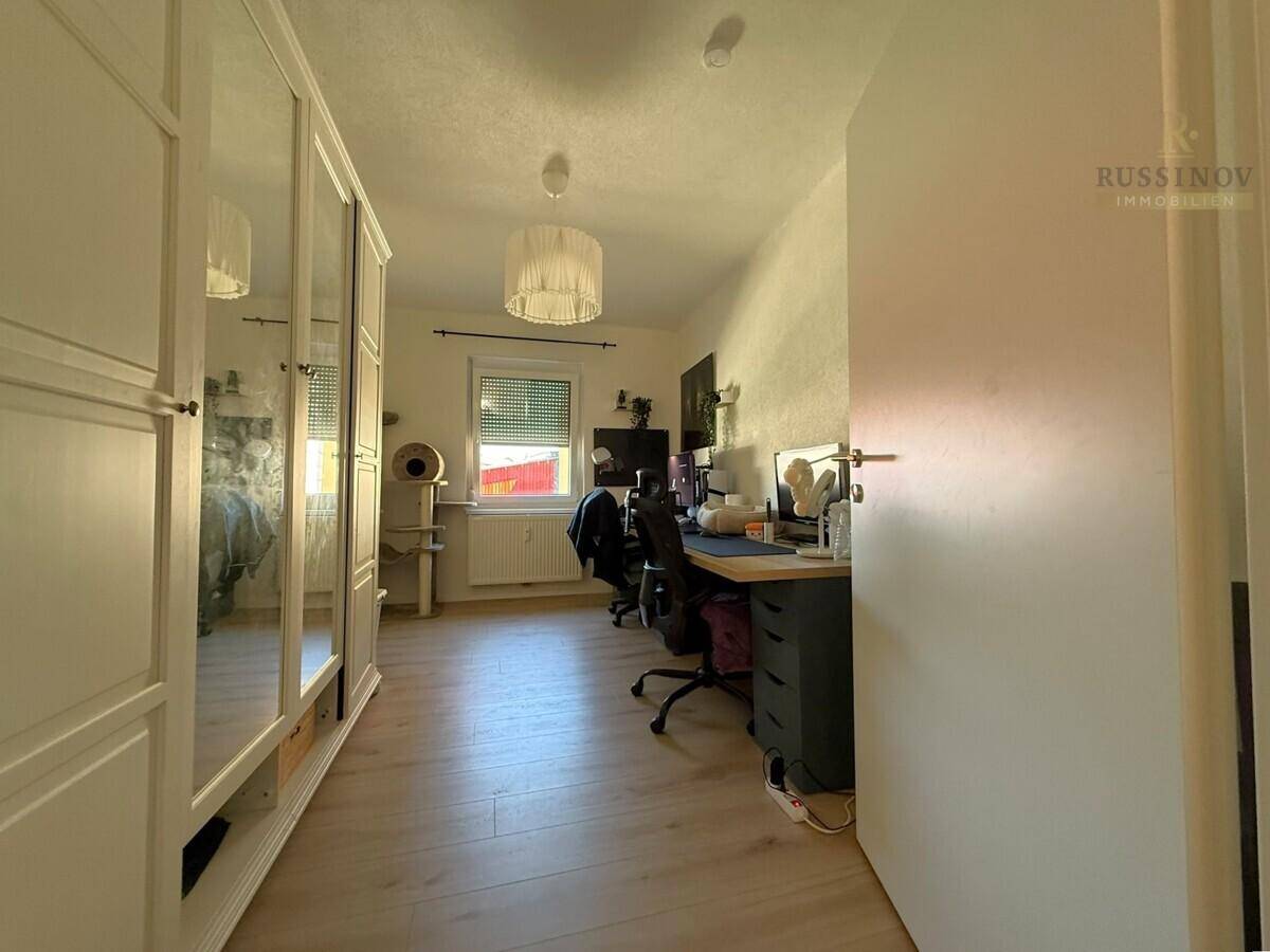 Arbeitszimmer mit Schreibtisch, Bürostuhl und großem Spiegelschrank.