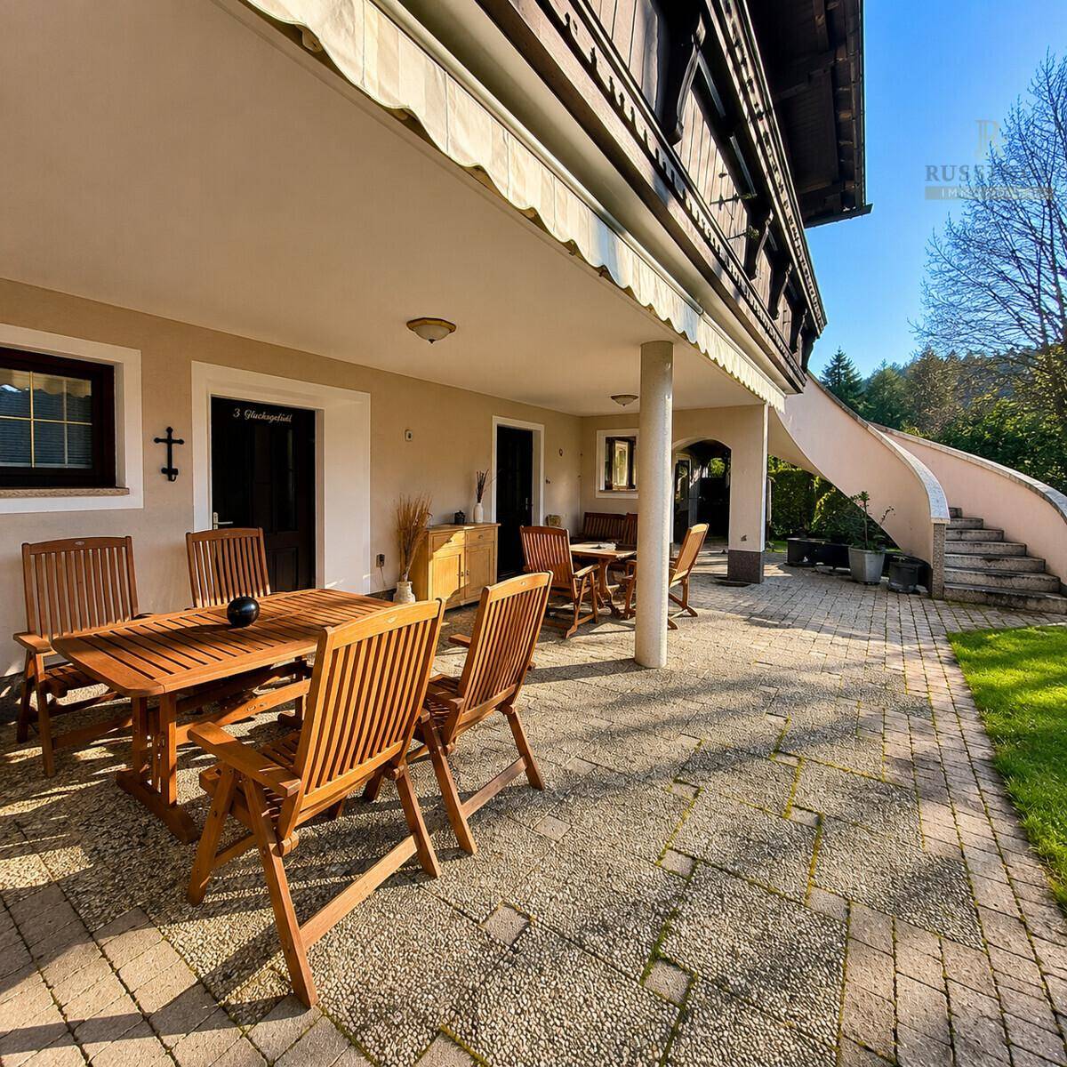 Geräumige Terrasse mit Holztischen und Stühlen, ideal für Mahlzeiten im Freien und Entspannung.