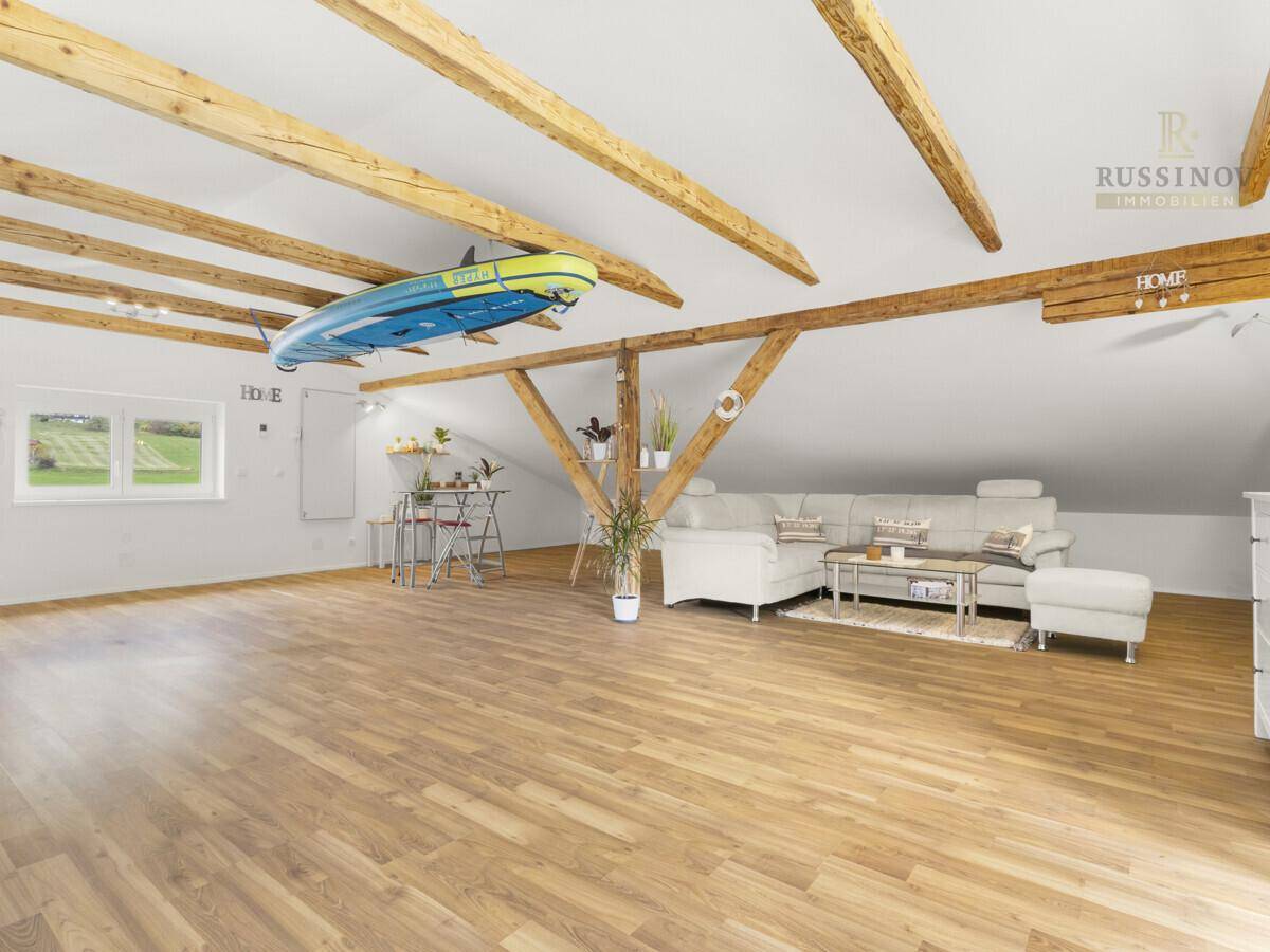 Heller, offener Dachbodenbereich mit Holzbalken und gemütlicher Sitzecke.