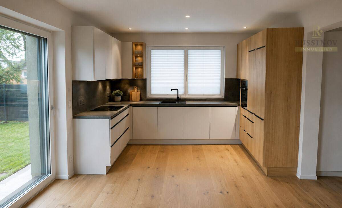 Helle, moderne Küche mit Holz- und weißen Fronten, dunkler Arbeitsplatte und Zugang zum Garten.