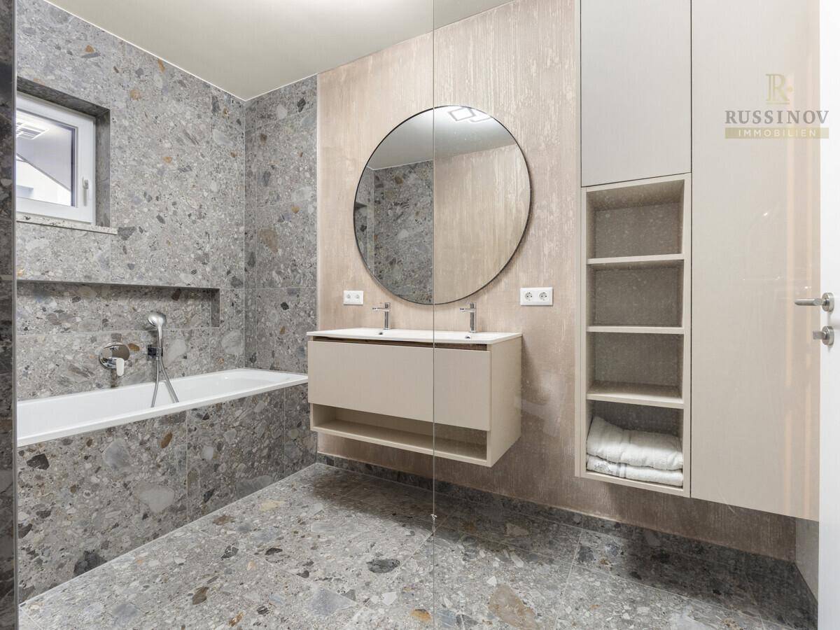 Modernes Badezimmer mit Badewanne, Doppelwaschbecken und stilvollen grauen Fliesen.