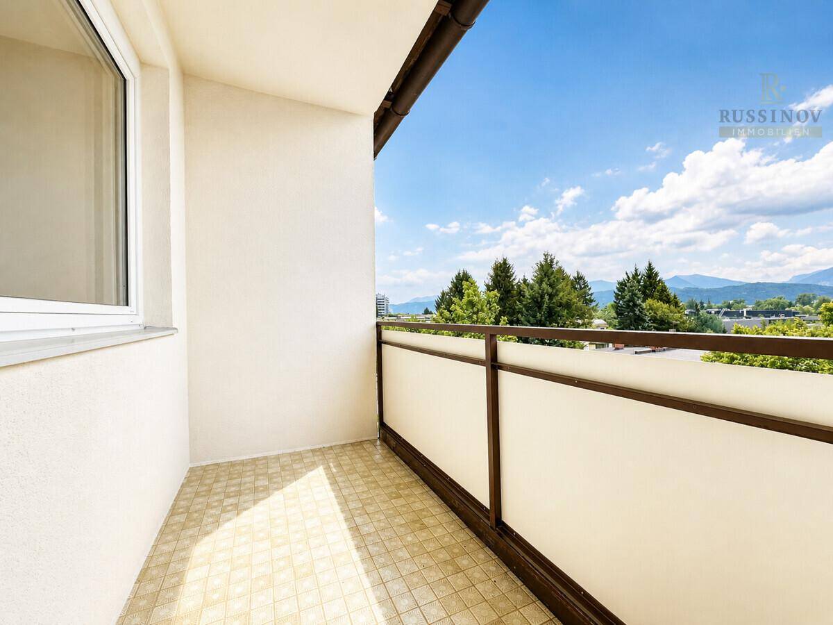 Kleiner Balkon mit Fliesenboden und schöner Aussicht auf die Umgebung und Berge.