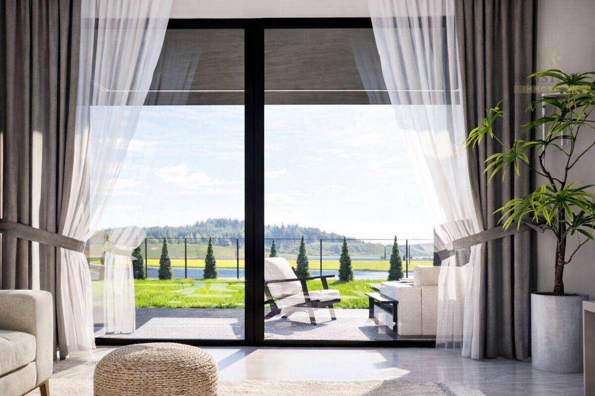 Große Fensterfront im Wohnzimmer bietet einen weiten Blick auf die umliegende grüne Landschaft.