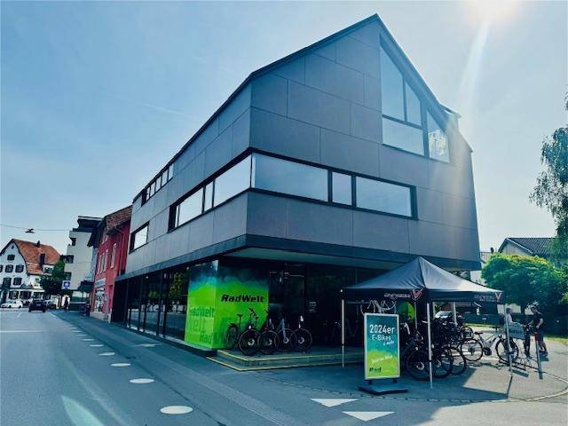 Modernes Geschäftsgebäude mit markanter Architektur, großen Fenstern und einer Fahrradhandlung im Erdgeschoss.