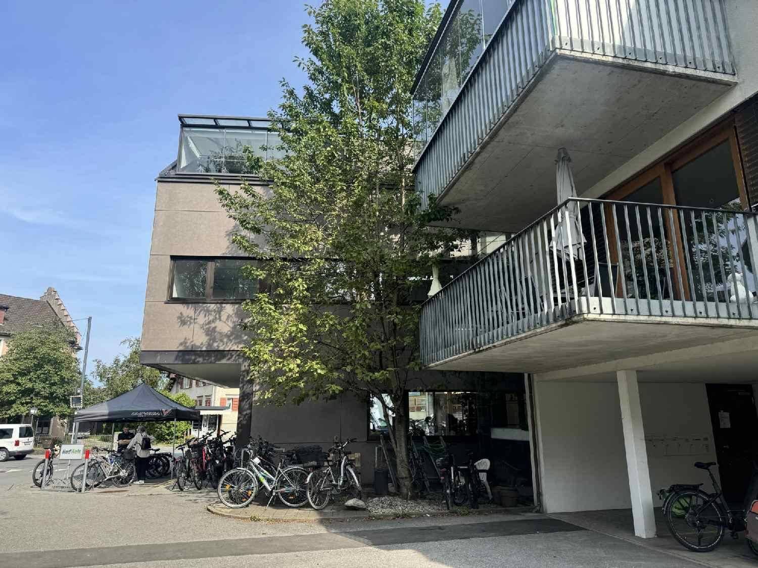 Mehrstöckiges Gebäude mit mehreren Balkonen und Fahrradabstellplätzen im Freien.
