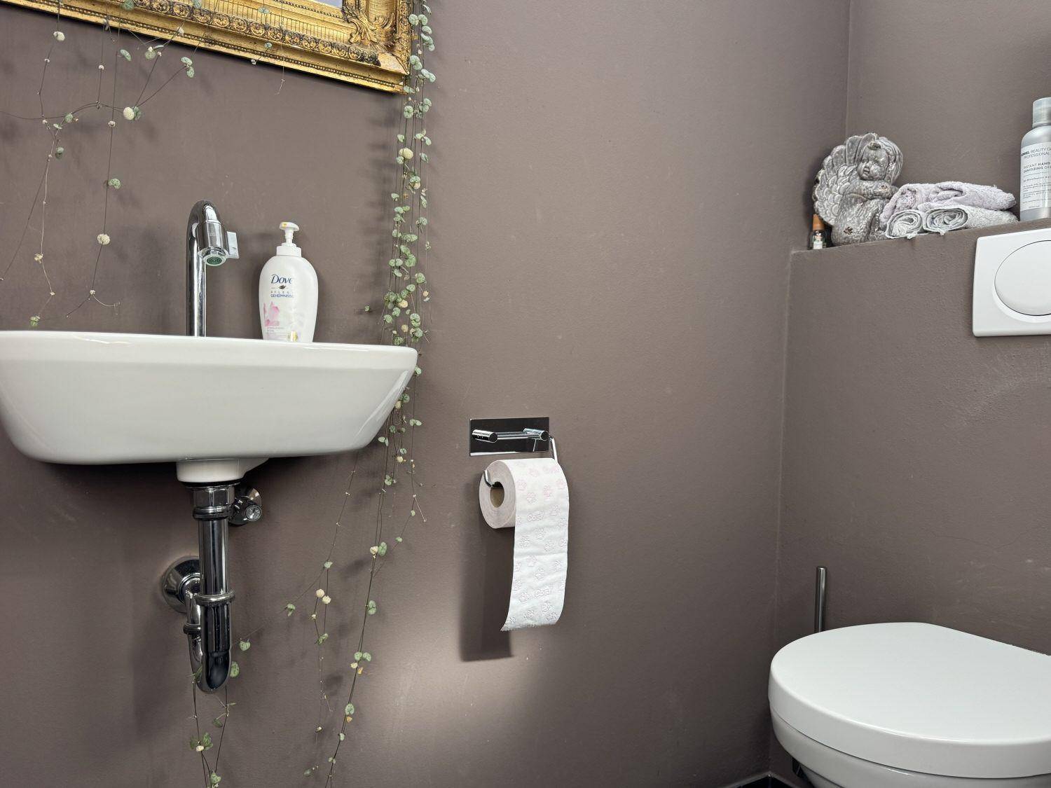 Modernes Gäste-WC mit kleinem Waschbecken, Wand-WC und braunen Wänden.