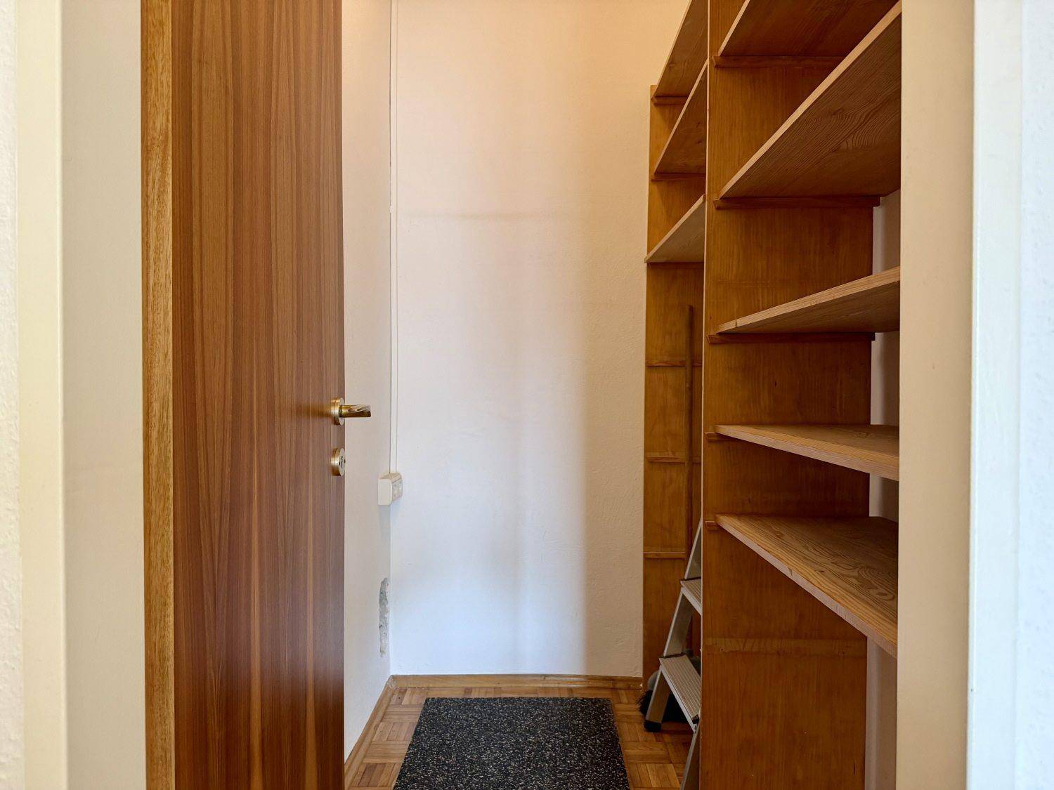 Praktischer Abstellraum mit Holzregalen und Parkettboden für zusätzlichen Stauraum.