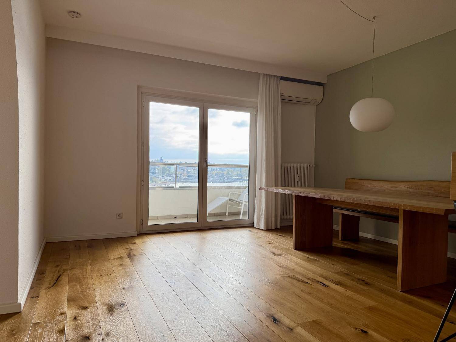 Essbereich mit großem Holztisch, Balkonzugang und Klimaanlage für Komfort.