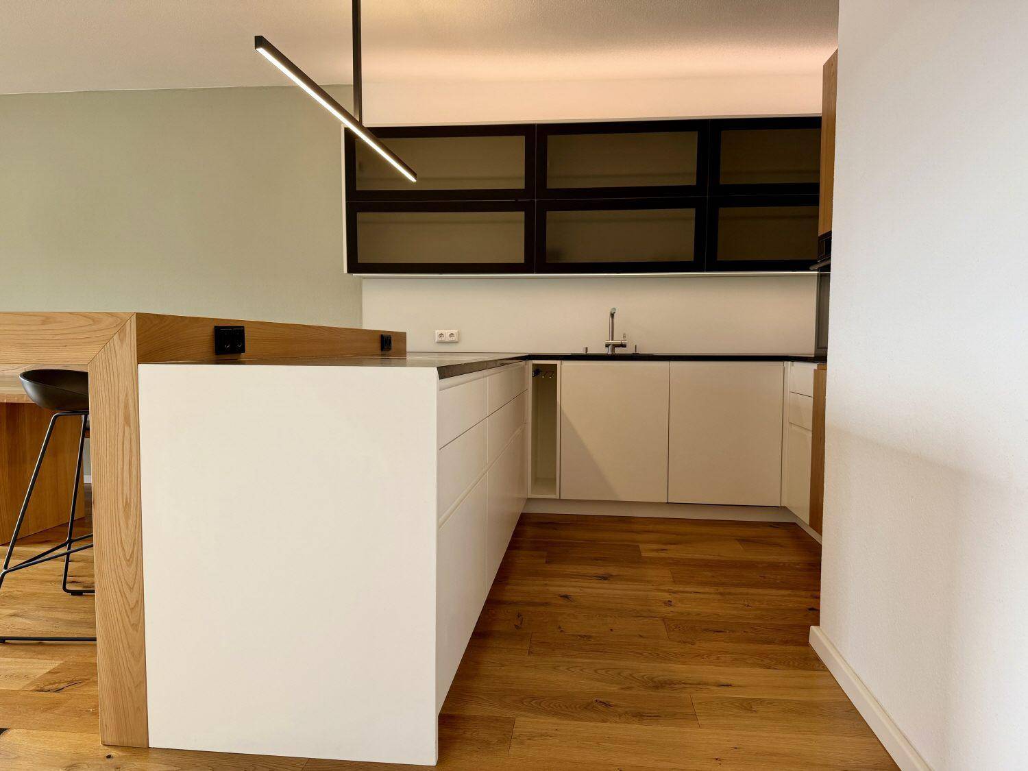 Funktionale moderne Küche mit Kücheninsel, weißen Unterschränken und dunkler Arbeitsplatte.